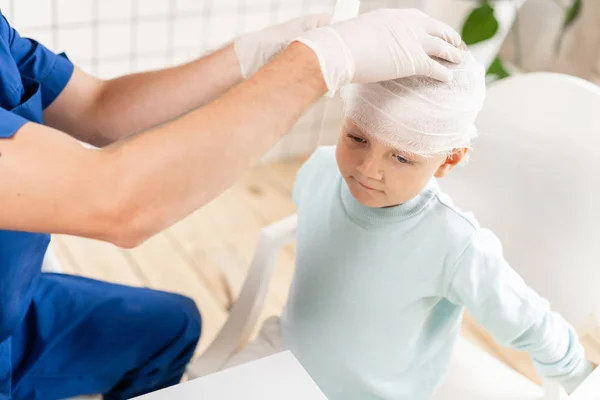Sport letsel. Arts maakt bandage op hoofd patiënt, in het ziekenhuis. — Stockfoto