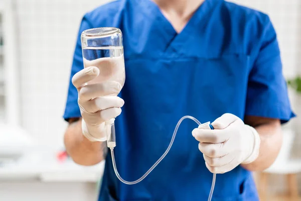 Doktor mavi üniformalı, damla iv ve infüzyon pompası tutuyor. Tıbbi tedavi acil kavram... Hastanede acil serviste ciddi hasta için intravenöz sıvı.