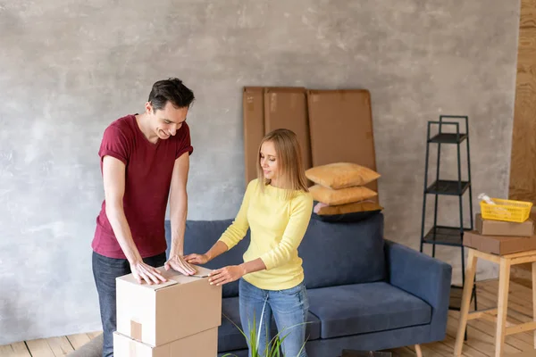 Pessoas felizes embalando caixa de papelão, conceito de mudança de casa. Casal jovem se mudando para um novo apartamento juntos. Conceito de recolocação — Fotografia de Stock