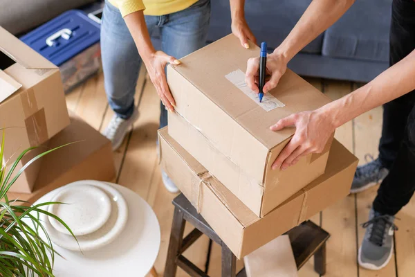 Fechar a caixa de papelão de embalagem de mão, conceito de mudança de casa. Casal jovem se mudando para um novo apartamento juntos. Conceito de recolocação — Fotografia de Stock