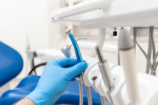 Mão de perto do dentista na luva detém turbina dental de alta velocidade. Escritório onde o dentista realiza inspeção e conclui. — Fotografia de Stock