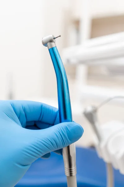 Κοντινό χέρι οδοντίατρου στο γάντι κρατά οδοντιατρική τουρμπίνα υψηλής ταχύτητας. Γραφείο όπου ο οδοντίατρος διεξάγει επιθεώρηση και καταλήγει. — Φωτογραφία Αρχείου