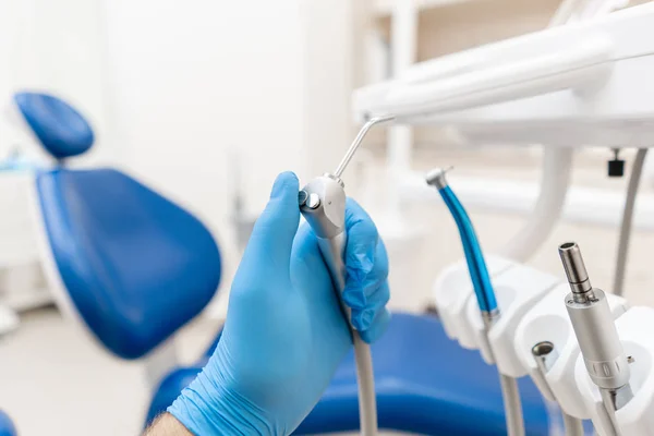 Mão de perto do dentista na luva segura Gun água dental e ar. .. Escritório onde o dentista realiza a inspeção e conclui. Escritório onde o dentista realiza inspeção e conclui . — Fotografia de Stock