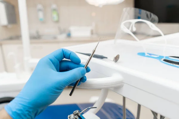 Eldivendeki diş hekiminin eli alet sondası tutar. . Diş hekimi kliniğinde stomatological alet. Klinikte diş işleri. Diş hekiminin muayene yaptığı ve sonuçlandırdığı ofis. — Stok fotoğraf
