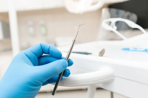 The hand of the dentist in the glove holds tool probe. . Stomatological instrument in the dentist clinic. Dental work in clinic. Office where dentist conducts inspection and concludes. — Stock Photo, Image