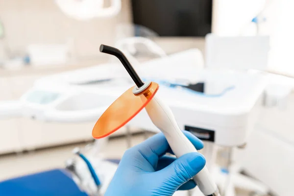 Diş polimerizasyonu lambası dişçi elinde, ultraviyole ışık ve lazerle. Dişçi kliniğindeki stomatolojik alet. Tıp, sağlık, stomatoloji kavramı. — Stok fotoğraf