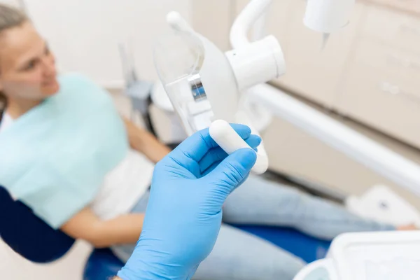 Κοντινό χέρι του οδοντίατρου στο γάντι ρυθμίζει τη λάμπα. Ο ασθενής σε μπλε καρέκλα στο παρασκήνιο. Γραφείο όπου ο οδοντίατρος διεξάγει επιθεώρηση και. — Φωτογραφία Αρχείου