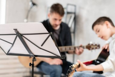 Gitar çalan öğretmen ve genç öğrencinin önünde duran müzik sayfası