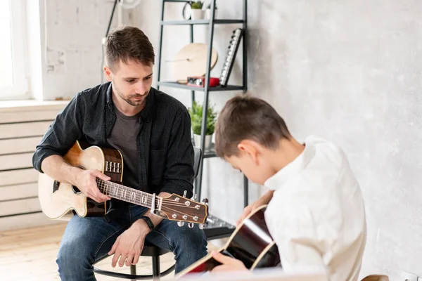 Bambino imparare a suonare la chitarra mentre il fratello maggiore guarda a lui — Foto Stock