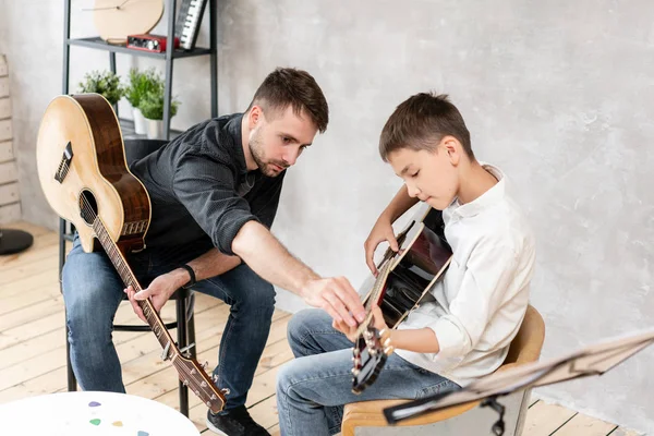 Due fratelli che suonano la chitarra. Il fratello maggiore insegna ai più piccoli a suonare correttamente gli accordi — Foto Stock