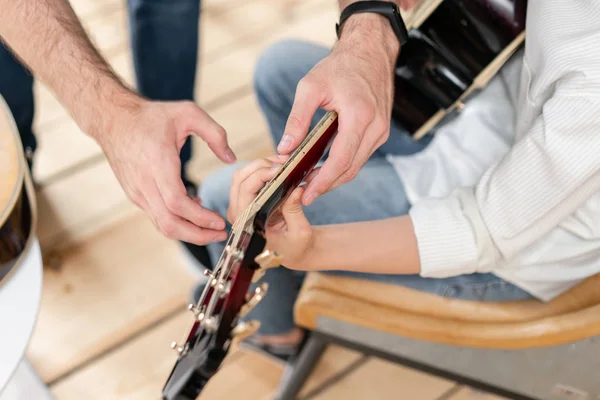 Primo piano della chitarra acustica nelle mani del ragazzo in camicia bianca, che impara a suonare gli accordi alla chitarra — Foto Stock