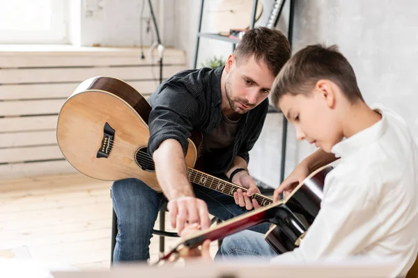 Deux frères jouant de la guitare. Le frère aîné enseigne au plus jeune à jouer correctement des accords — Photo