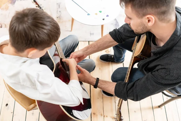 Un tutor personale spiega al suo giovane studente come suonare correttamente gli accordi studiati. Educazione musicale a casa — Foto Stock