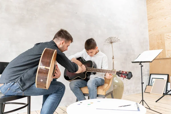 Two brother playing guitar. Older brother teaches younger one to play chords correctly — Stock Photo, Image