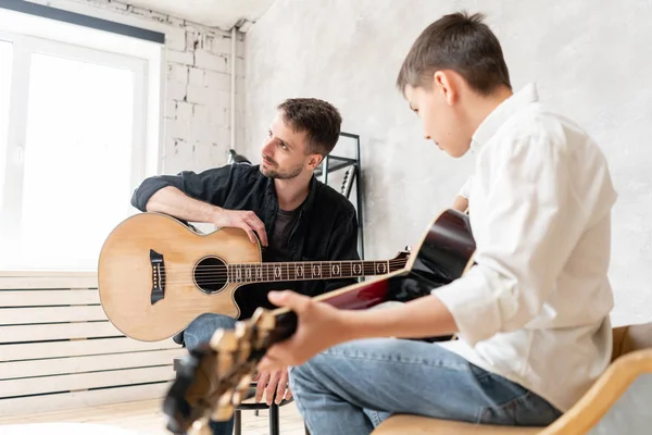 Un insegnante di musica professionista ascolta i suoni prodotti dal suo studente suonando la chitarra — Foto Stock