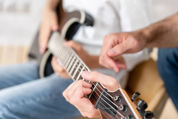 L'uomo adulto aiuta il suo fratellino a imparare a suonare la chitarra elettrica — Foto Stock