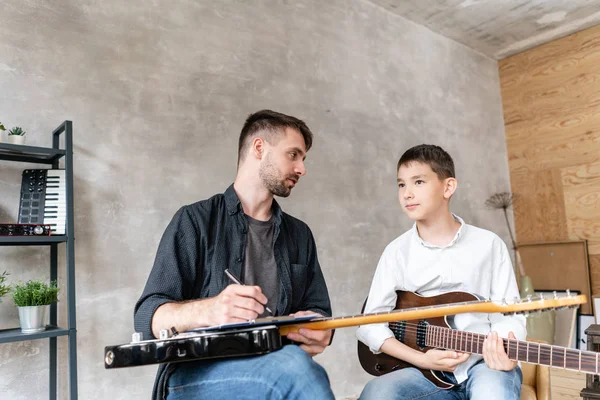 Un tutor personale scrive note sullo spartito musicale per il suo studente e spiega come suonarle . — Foto Stock