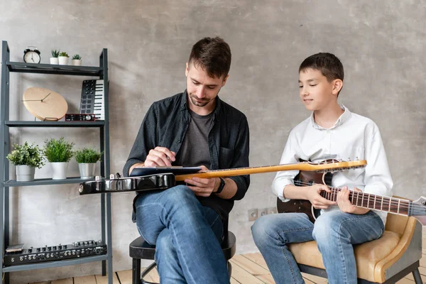 Giovane studente ascoltando i suoi tutor lezione di suonare la chitarra elettrica . — Foto Stock