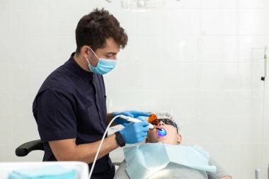 Uv lamba sıyrık ile incelenmiş ağzı ise genç çocuk diş hekimi koltuğuna yatıyor