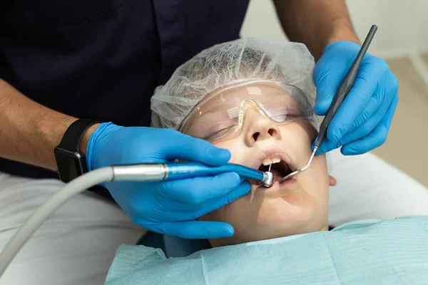 Dientes de perforación estomatólogo del paciente que se encuentra en la silla del dentista — Foto de Stock