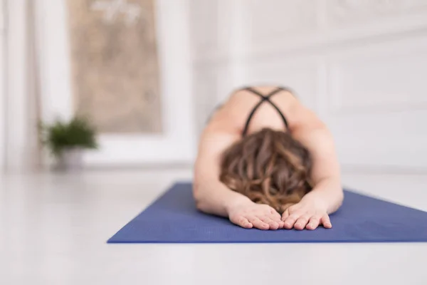 Blonde tiener legt op blauw tapijt in Childs pose. Selectieve focus. Lege ruimte voor tekst — Stockfoto