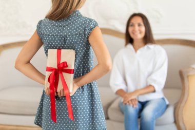 Küçük kız, annesi için kendi arkasında hediye kutusu saklıyor. Seçici odak