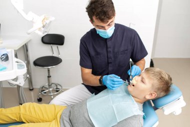 Kendine güvenen diş hekimi, hastalarının diş etlerini kontrol etmek için ayna ve diş sondası kullanıyor