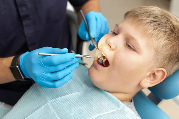 Primo piano del giovane ragazzo sdraiato sulla sedia dentale ed è in fase di esame da un medico — Foto Stock