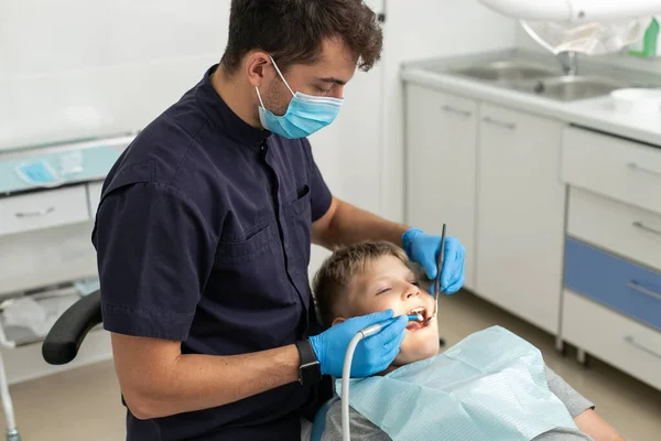 Dentist in black shirt drilling tooth of his young patient — Stock Photo, Image