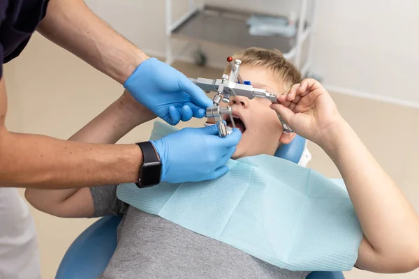 Kleine jongen ligt op stoel terwijl tandarts opknappen orthodontische boog — Stockfoto