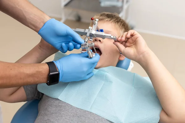Bambino sdraiato sulla sedia mentre il dentista fissa l'arco ortodontico — Foto Stock