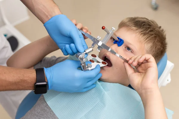 Jonge jongen met orthodontische boog, terwijl zijn tandarts zet het goed op — Stockfoto