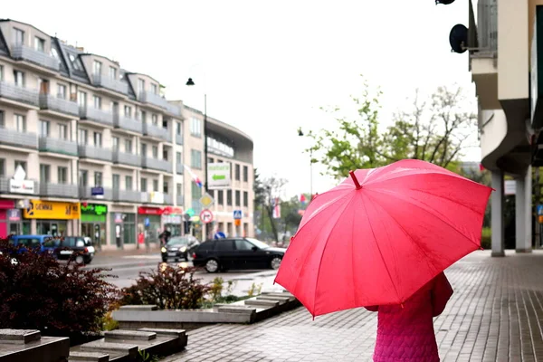 Sokakta yağmurun altında kırmızı şemsiyeli küçük kız