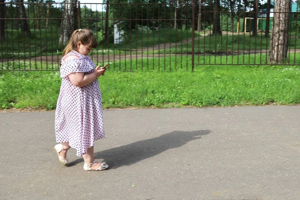 Küçük Tombul Kız Issız Bir Park Yolunda Yürüyor Akıllı Telefona — Stok fotoğraf