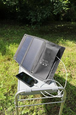 Akıllı telefon güneş enerjisiyle şarj oluyor. Güneşli bir günde, dikey formatta.