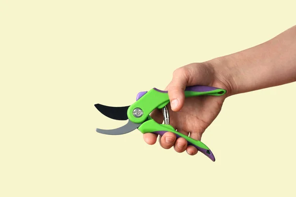 Hand holds garden pruning shears. Isolated on beige background close-up with copy space