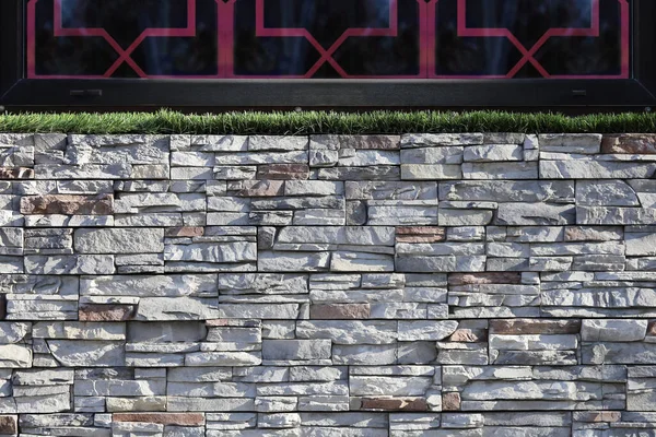 Wall decorations stone with display window pattern. Natural stone blocks textured surface and artificial green grass above