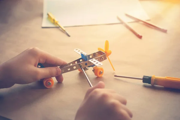 Kinderen handen met speelgoed ijzeren vliegtuig. Metalen constructor met schroevendraaiers. Droom, speel en creëer — Stockfoto