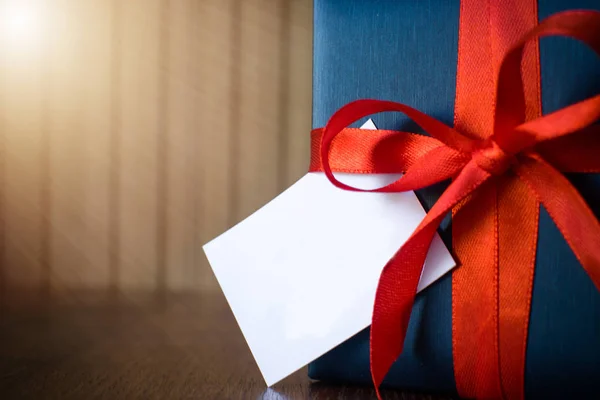 Fathers day. Gift package wrapped with blue paper and rope with a red ribbon on wooden background. Copyspace