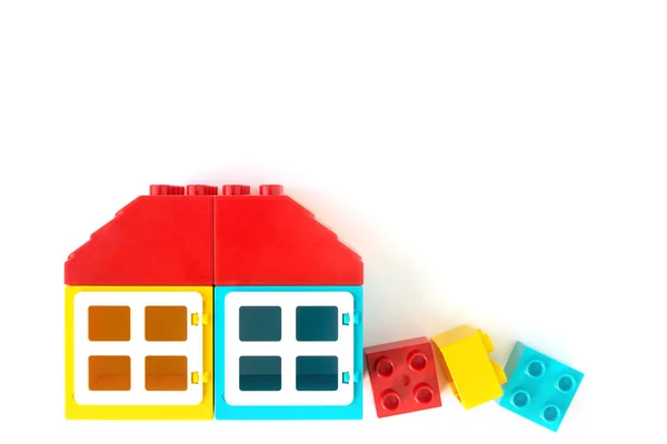 Casa feita de tijolos pequenos e grandes construtor de plástico no fundo branco. Brinquedos populares . — Fotografia de Stock
