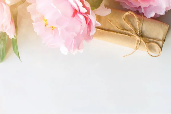 Bouquet di fiori e confezione regalo avvolto con carta artigianale su sfondo bianco con copyspace per testo. Concetto di saluto. Vista dall'alto — Foto Stock