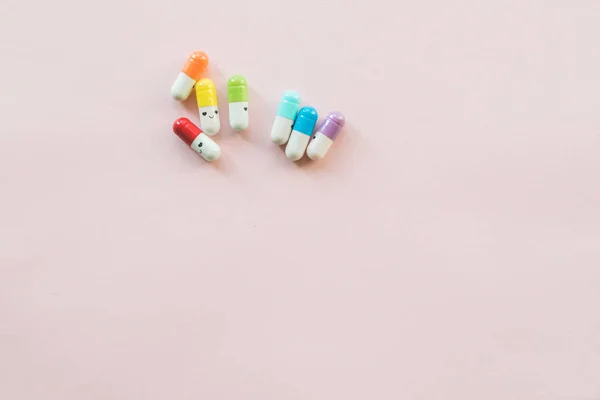 Grappige veelkleurige capsule op een pastel papier roze achtergrond. Copyspace — Stockfoto