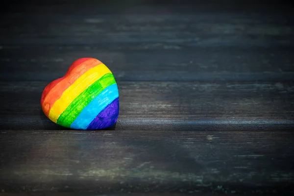 Декоративное сердце с радужными полосками на темном деревянном фоне. Флаг гордости ЛГБТ, символ лесбиянок, геев, бисексуалов, транссексуалов для социальных движений. Гомосексуальная любовь, концепция прав человека. Копирование пространства . — стоковое фото