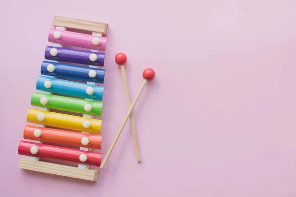 彩虹彩色木制玩具Xylophone在粉红色的百科地面。由金属和木材制成的玩具格洛克金斯皮尔。复制空间 — 图库照片