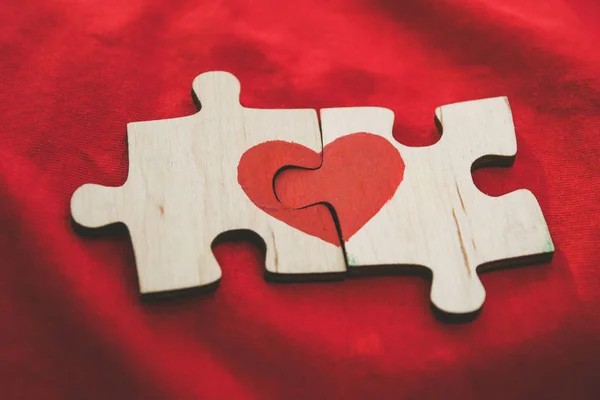 Red Heart készül a darab a fából készült puzzle fekvő egymás mellett piros háttér. Szerelmi koncepció. Szent Valentin-nap — Stock Fotó