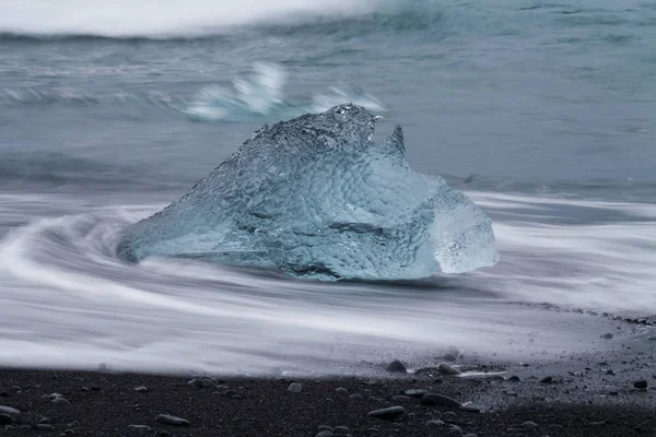 Diamond beach Jokulsarlon lagoon, İzlanda yakınındaki siyah kum ile şaşırtıcı şeffaf mavi buzdağı parçalar. Yavrulama buz. Su uzun pozlama. — Stok fotoğraf