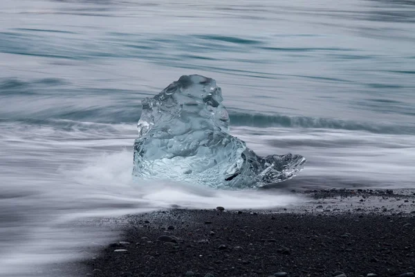 Diamond beach Jokulsarlon lagoon, İzlanda yakınındaki siyah kum ile şaşırtıcı şeffaf mavi buzdağı parçalar. Yavrulama buz. Su uzun pozlama. — Stok fotoğraf