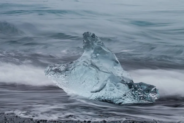 Amazing transparent blue iceberg pieces on Diamond beach with black sand near Jokulsarlon lagoon, Islândia. Parto de gelo. Exposição longa da água . — Fotografia de Stock