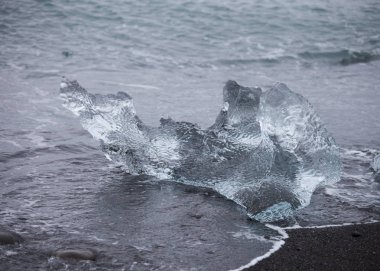 Diamond beach Jokulsarlon lagoon, İzlanda yakınındaki siyah kum ile şaşırtıcı şeffaf mavi buzdağı parçalar. Yavrulama buz. Su uzun pozlama.