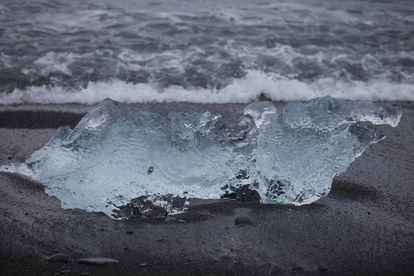Increíbles piezas de iceberg azul transparente en la playa de Diamond con arena negra cerca de la laguna de Jokulsarlon, Islandia. Terneros de hielo. Agua larga exposición . — Foto de Stock